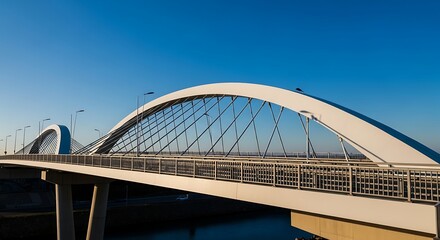 Obraz premium Modern Arch Bridge Structure Against Clear Blue Sky.