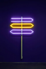 Obraz premium Vibrant Neon Street Sign Glowing with Purple and Yellow Directions for Urban Nighttime Wayfinding