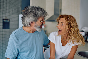 Cheerful senior couple enjoying laughter and conversation in their modern kitchen, sharing joyful moments and deepening their bond
