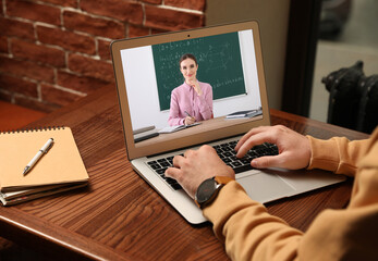 E-learning concept. Student having online video chat with teacher via laptop at desk, closeup