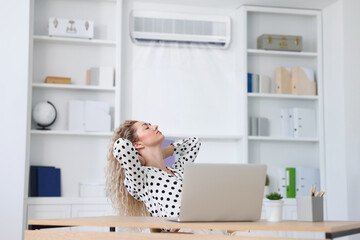 Woman enjoying comfortable temperature at work with air conditioning