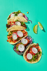 Corn tortilla tacos with beef, chicken and vegetable fillings with lime wedges on turquoise background