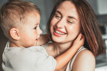 Happy cheerful mother holding her child in arms, enjoying family time and expressing love and joy.