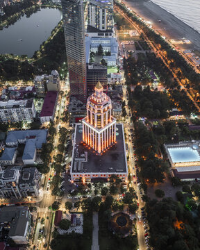Aerial view of the Radisson Blu Hotel Batumi glows amidst the urban tapestry, flanked by modern skyscrapers and verdant parks, a symphony of light and structure, Batumi, Adjara, Georgia.