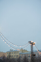 Fototapeta premium Festive string lights glow against historic city buildings