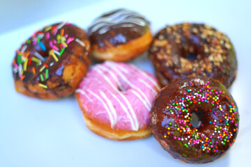 Delicious Glazed Donuts with Sprinkles on White Plate Background.
