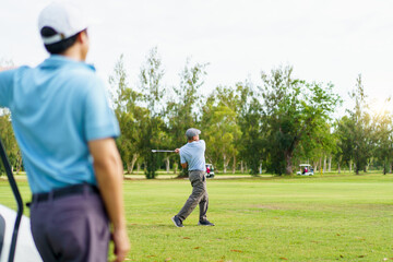 Obraz premium Elderly Asian man playing golf on green course. Active senior sport and lifestyle.