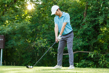 Asian man playing golf on green field in nature. Outdoor sport and leisure lifestyle.