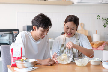 Happy couple making dough together in a cozy kitchen, smiling and enjoying the baking process.