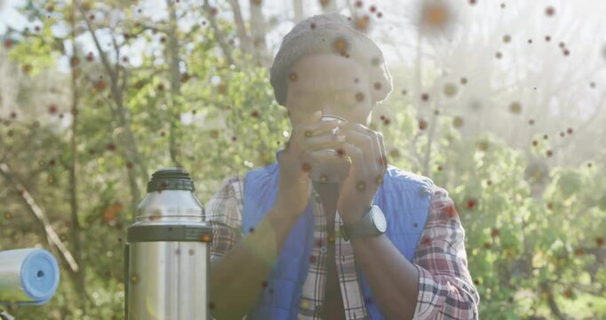 Coffee taster lifting cup and sipping drink in sunlit forest activating animated particles drifting