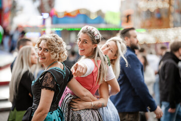 Three women wearing Bavarian dirndl costumes at cultural folk festivals like Munich Oktoberfest Gäubodenvolksfest in Straubing and Regensburg Dultfest Germany