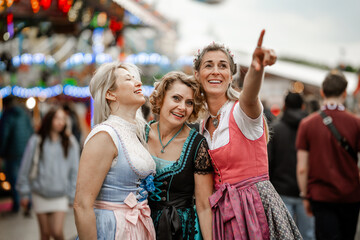 Fototapeta premium Three women dressed in colorful Bavarian costumes enjoy folk festivals like Munich Oktoberfest Gäubodenvolksfest in Straubing and Regensburg Dultfest Germany