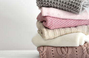 Stack of knitted folded clothing, winter autumn stacked woolen clothes. Sweaters folded on table empty copy space.