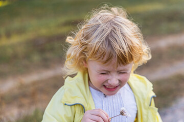 Young child enjoying a sunny day while playing with a flower in a grassy field during late afternoon