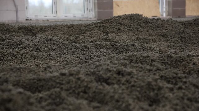 Close up views of liquid foam concrete screed and cement screed being spread and leveled, highlighting the textured surface and granular composition.