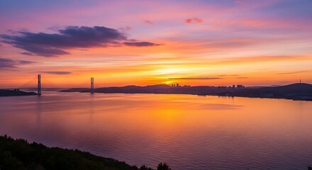Fototapeta premium Vibrant Sunset Over Water with Bridge and City Skyline.