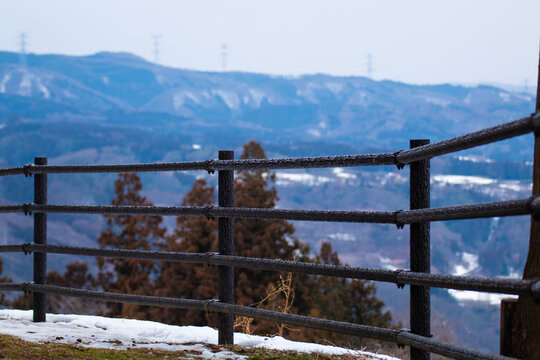 A rustic wooden fence stands before a snowy mountain landscape, symbolizing perspective, distance, and calm winter beauty.