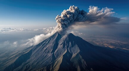 Aerial view of a large active volcano erupting, billowing smoke and ash against a vibrant blue sky