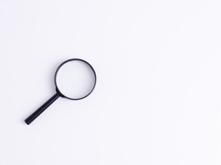 Minimalist flat lay of a black magnifying glass on white background with clear lens and copy space, symbolizing search, research, analysis, and investigation concepts.
