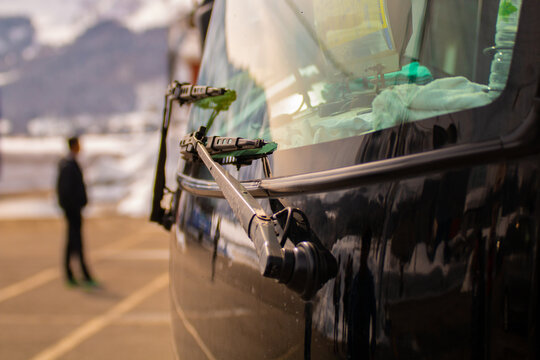 A detailed close-up of a car windshield wiper, with reflections on the glass and blurred background, creating an artistic urban travel mood.