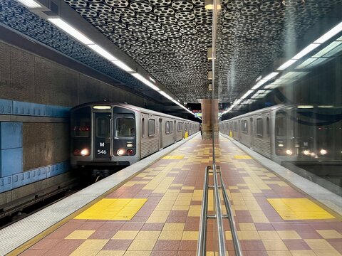 LOS ANGELES, CA, JULY 7, 2025: close view LA Metro subway train reflected on glass as it pulls into empty Hollywood and Vine station with striking film reel ceiling and vibrant mosaic floor tiles