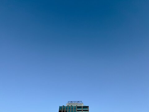 LOS ANGELES, CA, JUL 17, 2025: gradient blue sky transitioning from darker to lighter blue with top of modern building at bottom of image