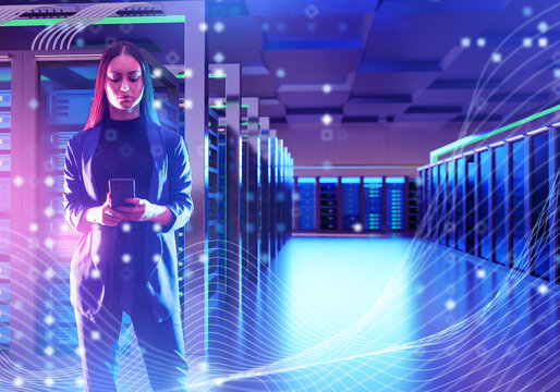 Businesswoman with smartphone standing in modern data center, digital network, cloud computing, cybersecurity, big data. Information Technology, Data center, Cloud computing.