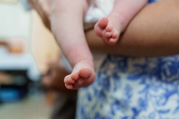 Naklejka premium Tender Baby Feet Held by Parent on Blue Fabric, Close-Up Focus on Delicate Skin, Soft Lighting, Infant Care Concept.