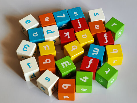 Colored wooden cubes, with letters and numbers on sides on grey background. Game childrens educational materials for learning process of making words from letters. Alphabet. ABC. Top view. Flat lay. - Powered by Adobe