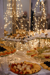 Elegant Dessert Table Display Illuminated with Fairy Lights. Lavish Fruit and Pastry Arrangement, Romantic Setting, Warm Golden Lighting