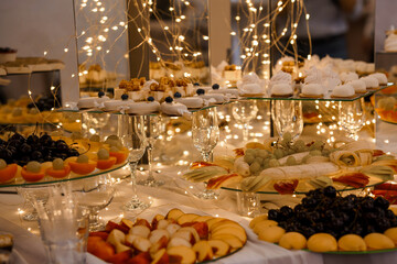 Lavish Dessert Buffet Setup: Fruits, Pastries, and Sparkling Lights at an Elegant Event Table, Golden Hues, Festive Celebration.