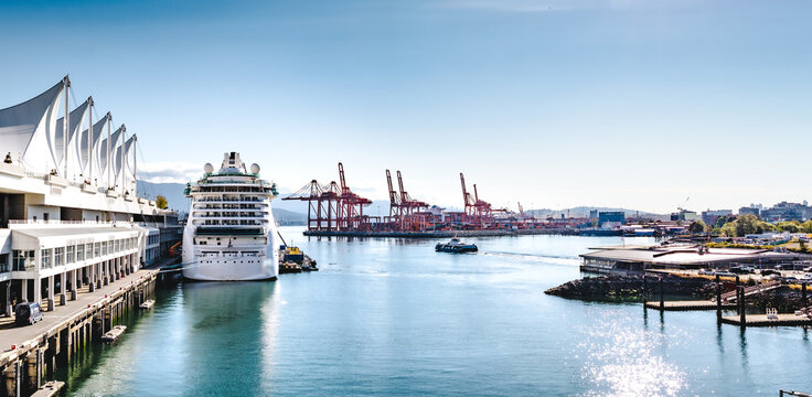 Vancouver Harbour panorama with cruise ship and seabus. Summer waterfront scene. Vancouver port activity with cruise ship docked, a ferry is leaving and many cranes and containers. Selective focus.