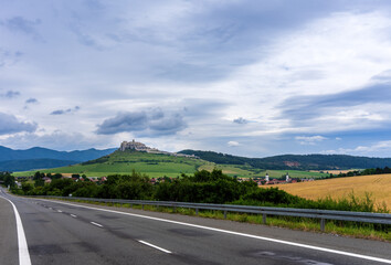 Ruins of Spiš Castle in eastern Slovakia, seen from afar with road in the foreground. A world heritage site.