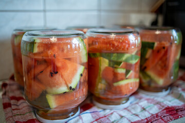 jars of pickled watermelons stand upside down on a towel