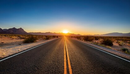 Fototapeta premium beautiful sunrise over an empty open road in a scenic desert landscape framed by distant mountains and a clear sky