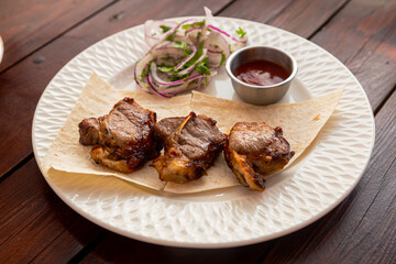 Lamb shashlik with fried tomato sauce and lavash on a white plate