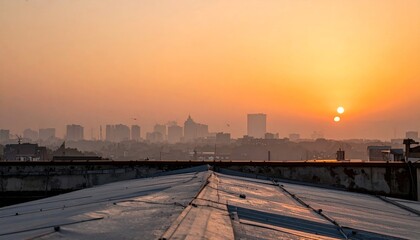 Naklejka premium Sunset Over City Skyline with Rooftops Silhouetted in Orange Glow