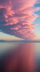 Fototapeta premium Pink cloud over sea at sunset, dramatic sky reflection in calm water, surreal seascape nature background