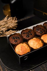 Close-up of chocolate chip and vanilla mini muffins in box, showing crumb texture and toppings. Dark studio food styling&mdash;ideal for packaging design, ads, menus, and social media.