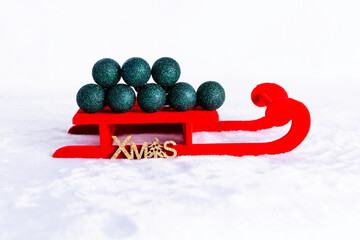 Red Christmas sleigh with green glitter Christmas ornaments on the snow