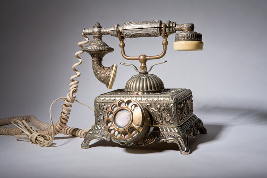 Vintage phone standing on a white table top on a white background.