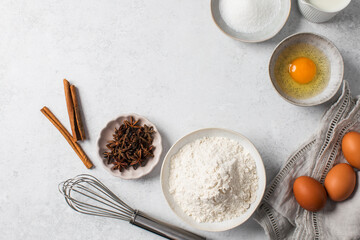 Baking ingredients flat lay with flour, eggs, sugar, and spices on marble surface. Copy space