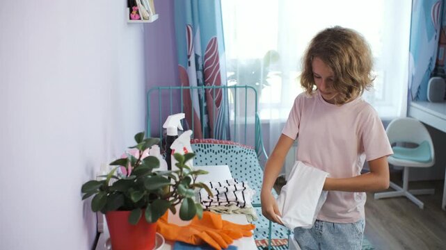 Teen girl tidies her room by folding clothes and placing them into a drawer. Household and chores concept