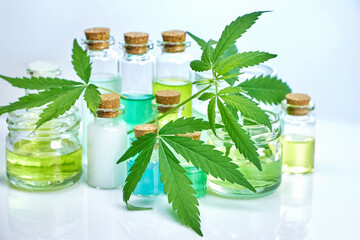 hemp leaves, jar with gel from hemp and bottles with hemp extracts on a blue background, concept of studying and applying useful properties in medicine, pharmaceuticals and cosmetology