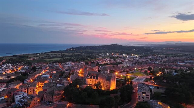 Altafulla, Spain aerial drone video of small Spanish town with an old castle at the top of the hill above the town at dusk