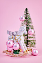 delicate New Year's composition with a toy horse and Christmas tree balls on a pink background, vertically