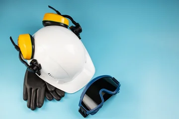 Yellow headphones with a white helmet and dark welding glasses on a blue background © Alexander