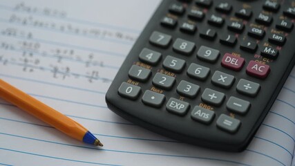 A scientific calculator and ballpoint pen lying on an open notebook with equations inside. Close up. - Powered by Adobe