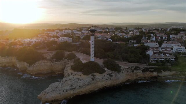 Torredembarra Lighthouse along the coast between Torredembarra and Altafulla, Spain aerial drone video at sunset