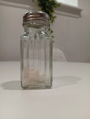 salt in a half-empty vintage glass salt shaker on a white table